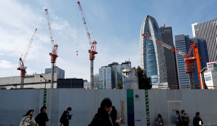 Passersby walk in front of a construction site in Tokyo, Japan on February 15, 2024